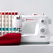 SINGER Elite ME457 sewing machine stitching red fabric with LED-lit workspace and high-speed mechanical performance