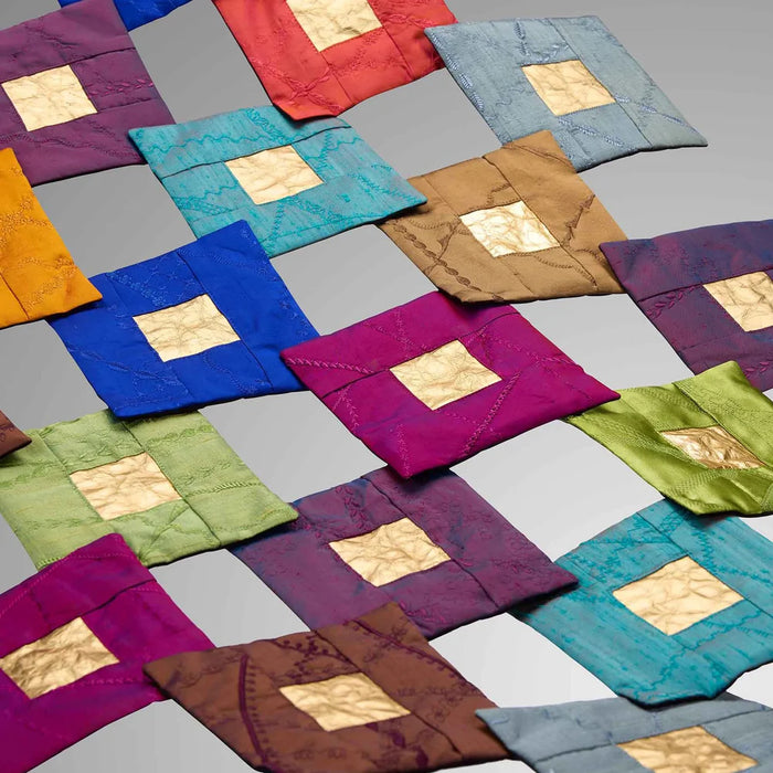 Colorful quilted fabric squares arranged in a pattern on a gray background