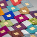 Colorful quilted fabric squares arranged in a pattern on a gray background