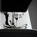 Close-up of a sewing machine needle and mechanism on a dark background
