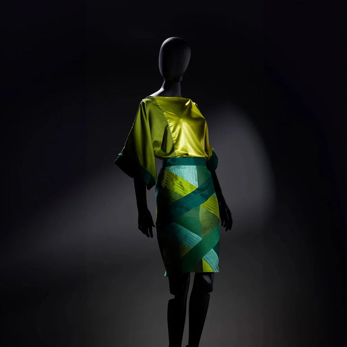 Mannequin wearing a green and yellow dress against a dark background