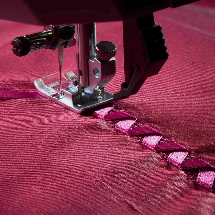 Sewing machine needle stitching a pattern on red fabric