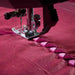 Sewing machine needle stitching a pattern on red fabric