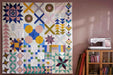Finished quilt hanging on wall with Husqvarna Viking EPIC QUILT 97 sewing machine displayed in a modern quilting studio