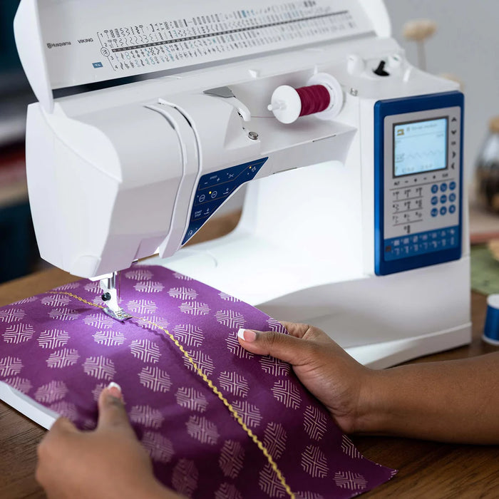 Husqvarna Viking Sapphire 930 sewing machine in use stitching decorative fabric with automatic needle control and illuminated work area