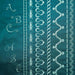 Teal fabric with white embroidery patterns including letters, leaves, and abstract designs.
